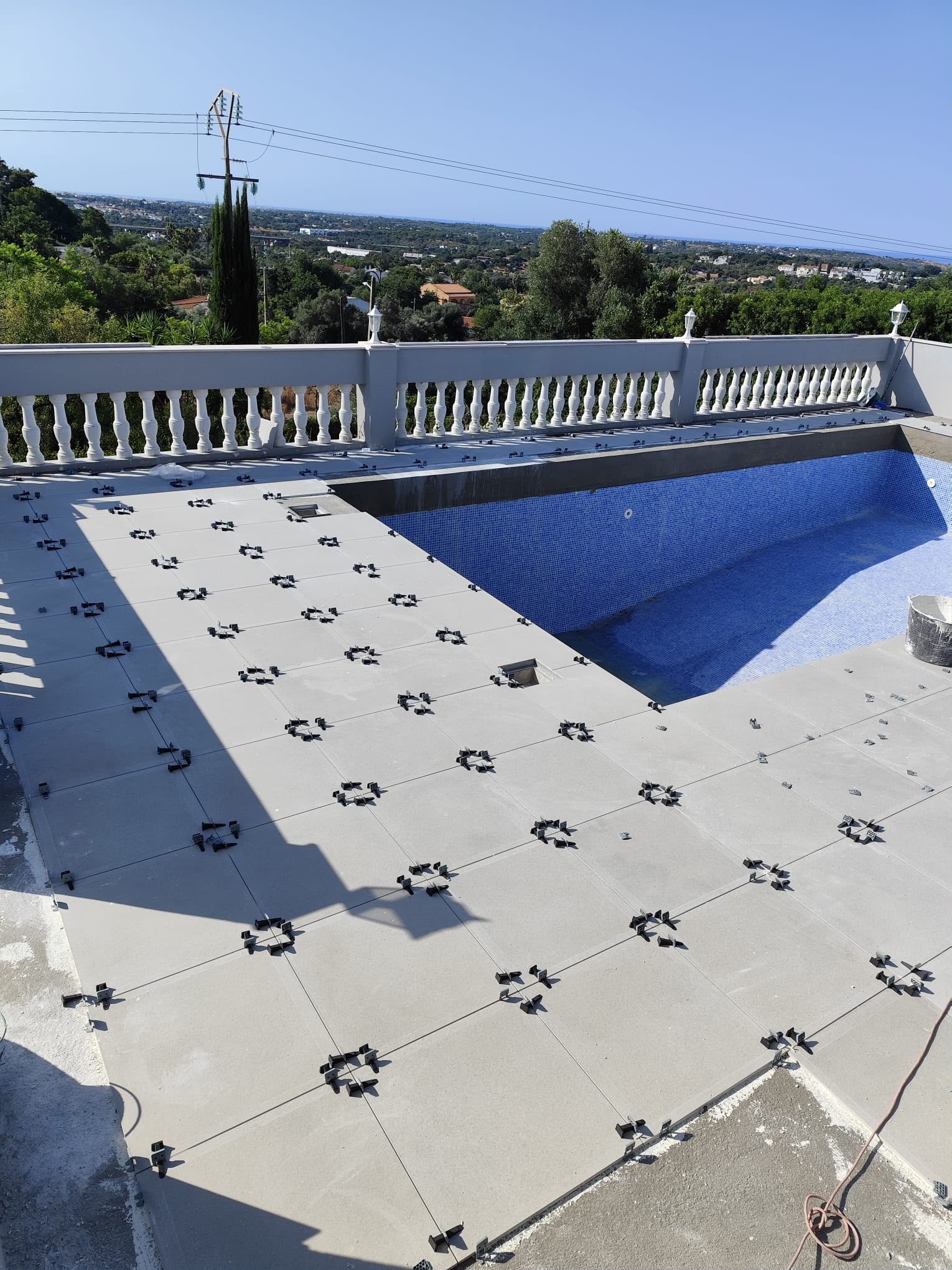 New patio tiles being installed around the pool
